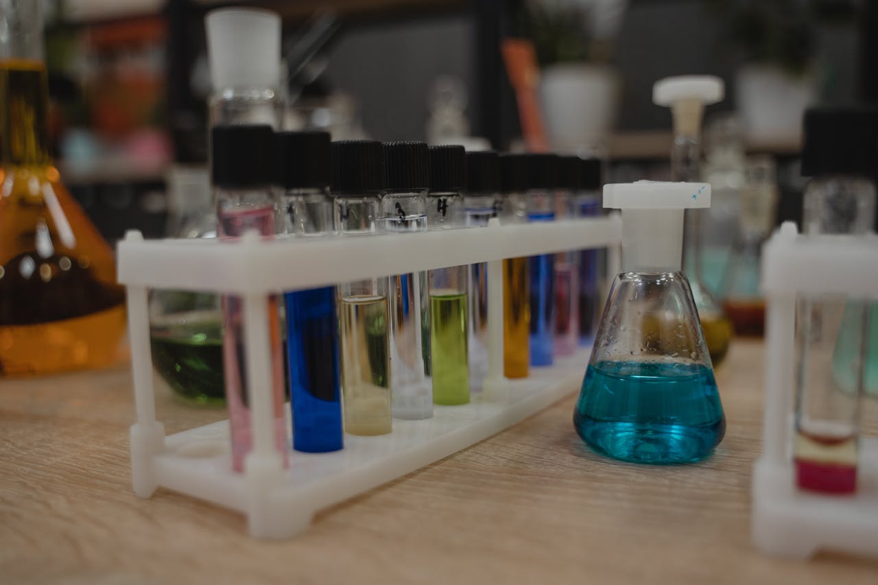 our-story A collection of colorful test tubes and flasks in a chemistry laboratory setting.