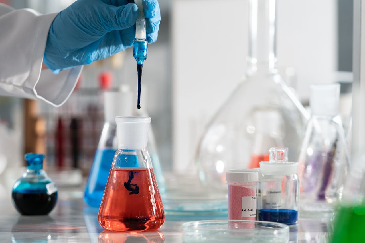 services-04 Scientist conducting a laboratory experiment with colorful chemical solutions and scientific glassware.
